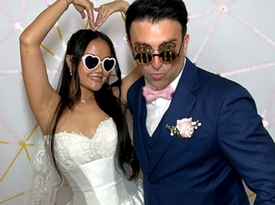 Bride making a heart above her head beside the groom